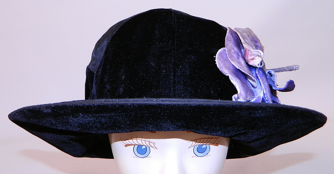 Vintage Hart Hats Black Silk Velvet Wide Brim Purple Flower Flapper Cloche Hat
This fabulous flapper cloche style hat has a form fitting style with an upturned wide brim which is wider on the sides and front, backed in black velvet and is fully lined inside the crown in black silk with a "Hart Hats Cleveland, New York, Paris" label.
