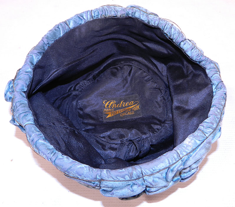 Vintage Ruched Cornflower Blue Gray Velvet Silver Lame Leaf Trim Toque Cloche Hat Lam&eacute;
This beautiful blue brimless toque style cloche hat is fully lined with a black silk fabric and a "Andrea Patterns Paris, New York, Chicago" label inside. 