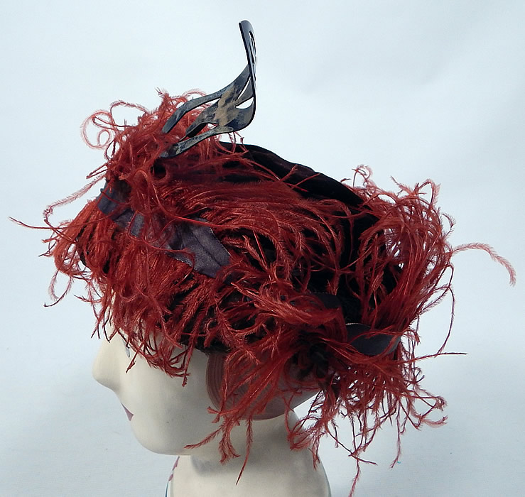 Vintage McGrath Millinery Belle Epoque Burgundy Velvet Feather Trim Toque Hat
The hat is made of a dark red burgundy wine color velvet fabric, with reddish orange ostrich feathers and gold lamé ribbon trim surrounding it.