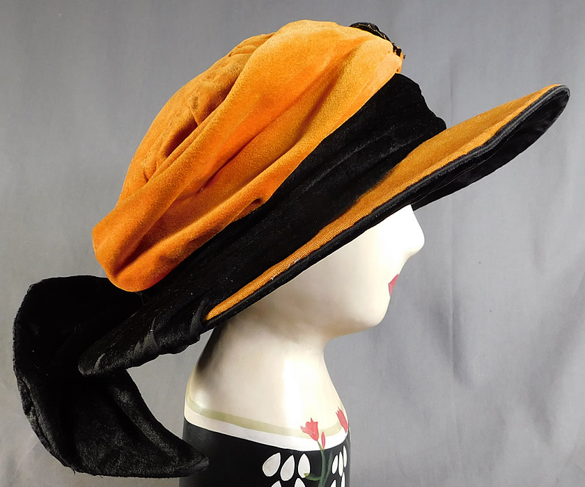 Vintage Harris Hat & Cloak Shop Orange Black Velvet Winged Wide Brim Cloche
This amazing artist palette shaped wide brim hat has a slouched round crown, black velvet hatband, wired winged trim on the back and black velvet lining backing the brim underneath.