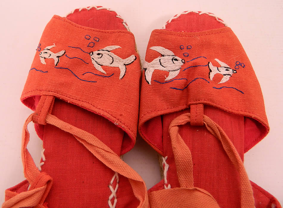 Vintage Red Linen Goldfish Ankle Tie Rope Sole Childrens Beach Sandal Shoes. They are made of a red linen fabric, with white embroidered goldfish designs on the front vamps. 