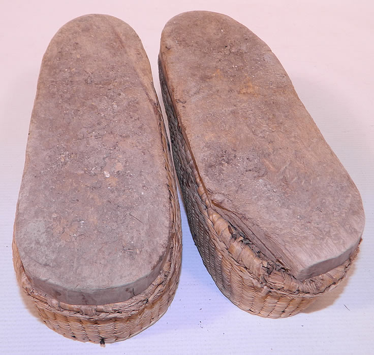 Antique Chinese Woven Braided Straw Hand Carved Wooden Farmers Shoes. The shoes measure 9 inches long and 3 inches wide. They are in good as found worn condition, with some wear to the straw and a chip along the edge of the wooden bottom sole. 