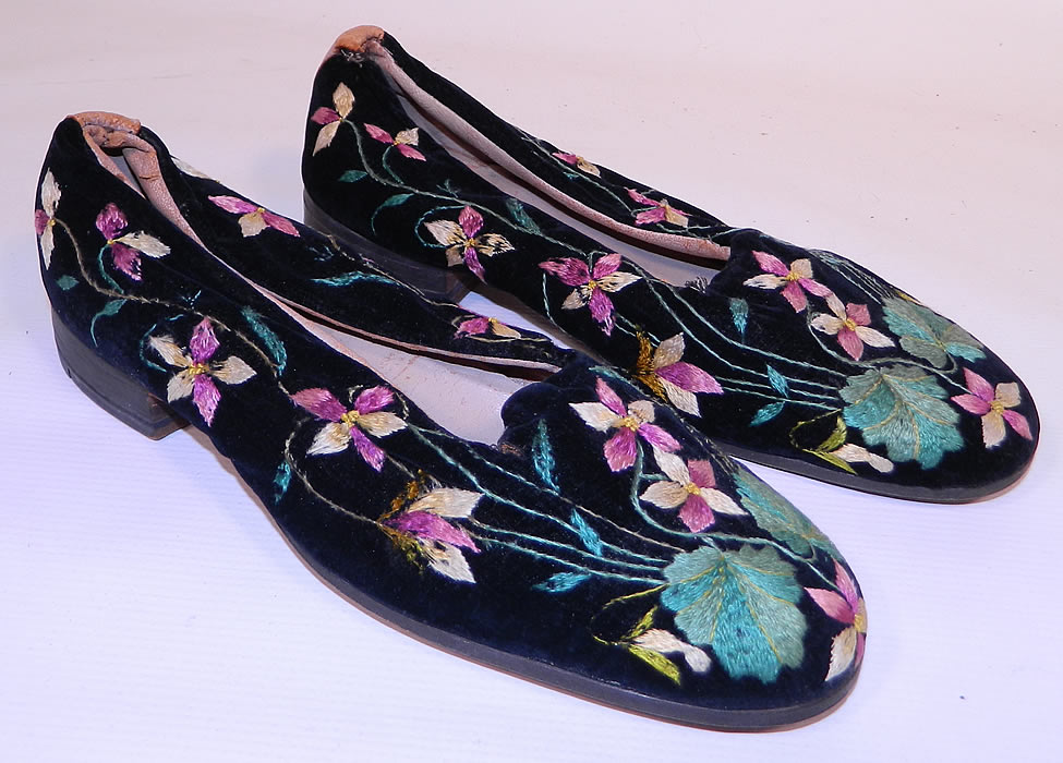 Victorian Black Velvet Violet Embroidered Men's Slipper Shoes. They are made of a black plush velvet fabric, with colorful purple violet flowers and leaves embroidered on it.