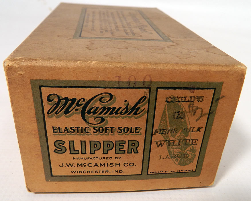 Vintage McCamish Funeral Burial Child's White Satin Slipper Shoes. This unique pair of unworn in the box, children's funeral burial slippers shoes measure 6 1/2 inches long and 2 inches wide. They are in excellent condition, with only some water spot stains on the cardboard box. These are a rare find which would make for a great mourning display!