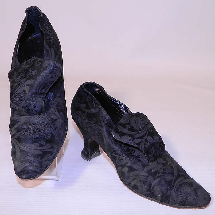 Vintage JW Robinson Co Los Angeles Edwardian Black Silk Damask Brocade Tongue Shoes. They are made of a black silk damask floral brocade patterned fabric. These beautiful black brocade evening shoes have a slip on style, with a large flared tongue and silk covered French Louis XV heels.