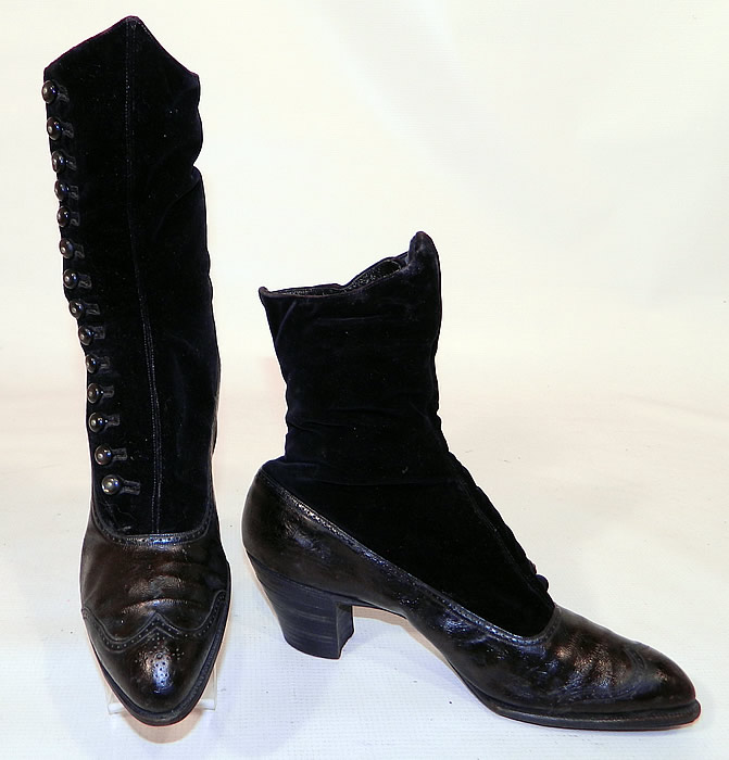 Victorian Black Velvet & Leather High Top Button Boots WH Tuttle Co Boston. The boots have pointed toes with decorative punch work designs on the front toes, 14 black shoe buttons along the side for closure and stacked black wooden cube heels.