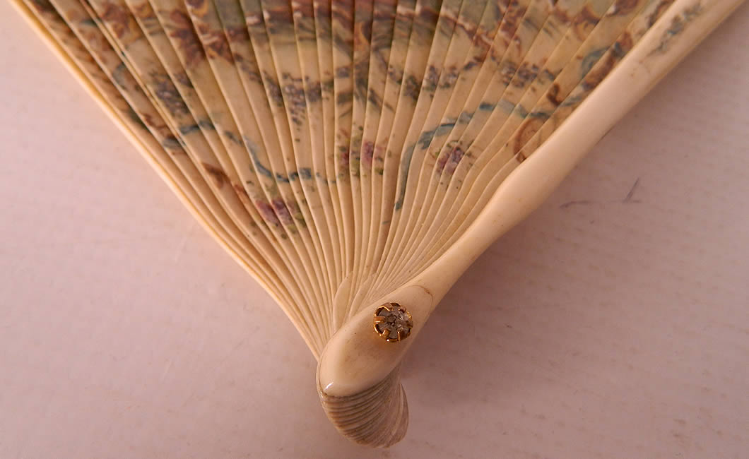Victorian Antique Hand Painted Figural Bone Small Brise Dance Fan. The sticks and guards are tied together and have blue silk ribbon woven along the top holding the sticks together and a paste diamond rivet holding the fan together at the bottom.