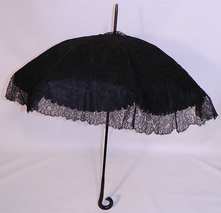 Edwardian Black Chantilly Lace Carved Ebony Handle  Parasol. There is a carved black ebony wood curled handle and metal capped tip finial top. This pretty parasol umbrella is lined in black silk, with a black metal frame inside. 