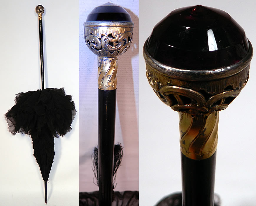 Edwardian Black Silk Ruched Ebony Amethyst Jeweled Handle Parasol. There is a black ebony wood stick handle and finial top, with a jeweled amethyst gold tone metal filigree round ball base handle and black silk tassel trim. 