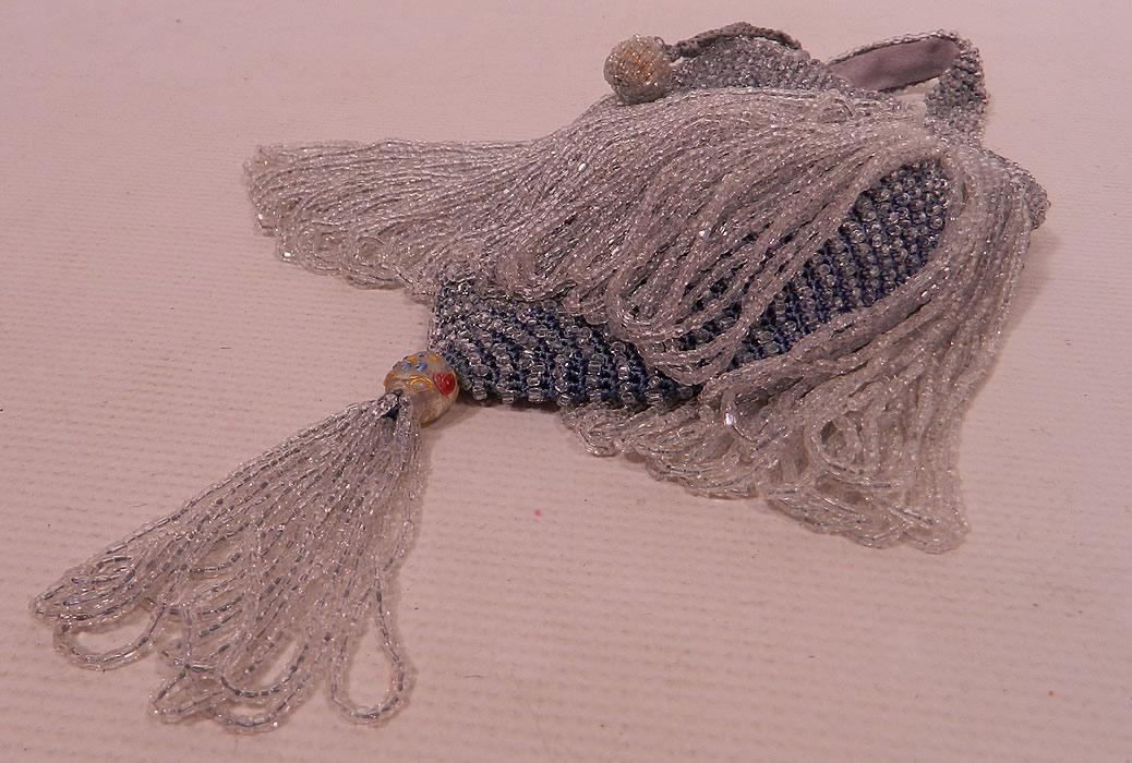 Vintage Periwinkle Blue Crystal Beaded Loop Fringe Tassel Drawstring Flapper Purse
There is a crystal beaded fringe tassel trim with hand painted colorful floral bead hanging down from the bottom. This fabulous flapper Art Deco handbag purse has an inner drawstring closure on top with silk rope ties, beaded ball trim ends and a beaded loop strap on top for carrying. 
