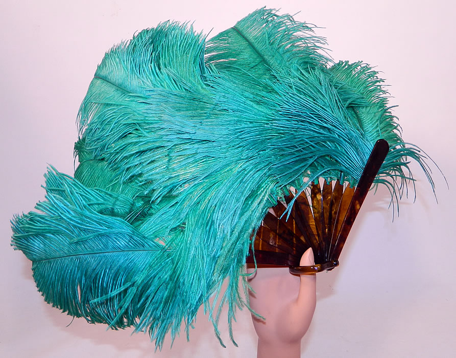 Vintage Art Deco Teal Blue Green Ostrich Feather Folding Flapper Fan
This vintage Art Deco teal blue green ostrich feather folding flapper fan dates from the 1920s. It is made of large fluffy teal bluish green color dyed ostrich feathers plumes.